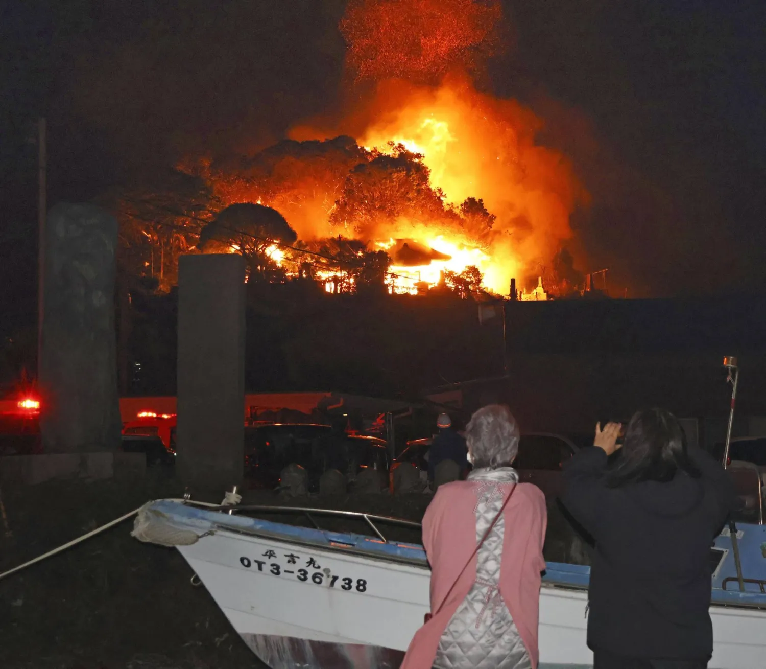 Residents watch flames rise from the site of a fire in Oita, southern Japan Tuesday, Nov. 18, 2025. (Kyodo News via AP)