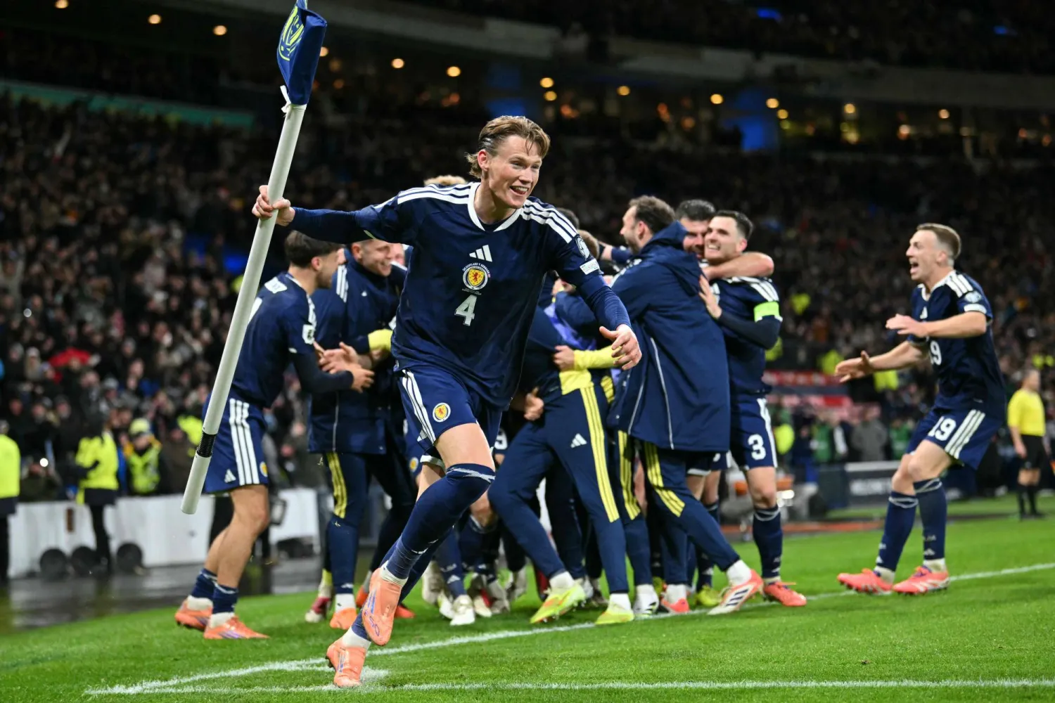 Scotland's midfielder #04 Scott McTominay grabs the corner flag as Scotland's midfielder #23 Kenny McLean celebrates with teammates after scoring his long-range last-kick of the game goal during the FIFA World Cup 2026 European qualification football match between Scotland and Denmark at Hampden Park in Glasgow on November 18, 2025. (AFP)
