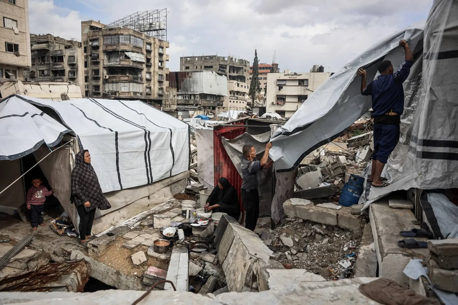 فلسطينيون يُعدون خيامهم مع هطول الأمطار الشتوية الأولى على مخيم للنازحين في مدينة غزة (أ.ف.ب)