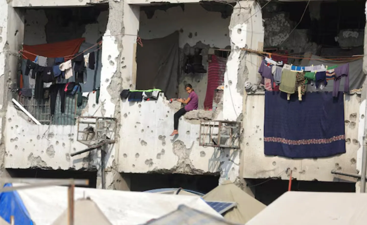 A displaced Palestinian girl sits on a wall of a damaged school where she has taken shelter in Gaza City, November 11. REUTERS/Dawoud Abu Alkas 