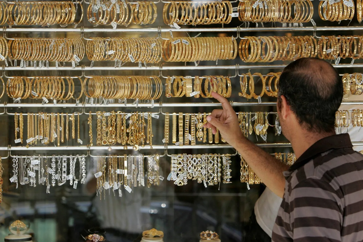 رجل أردني ينظر إلى أساور ذهبية معروضة في أحد المحال في سوق الذهب في عمان (رويترز)