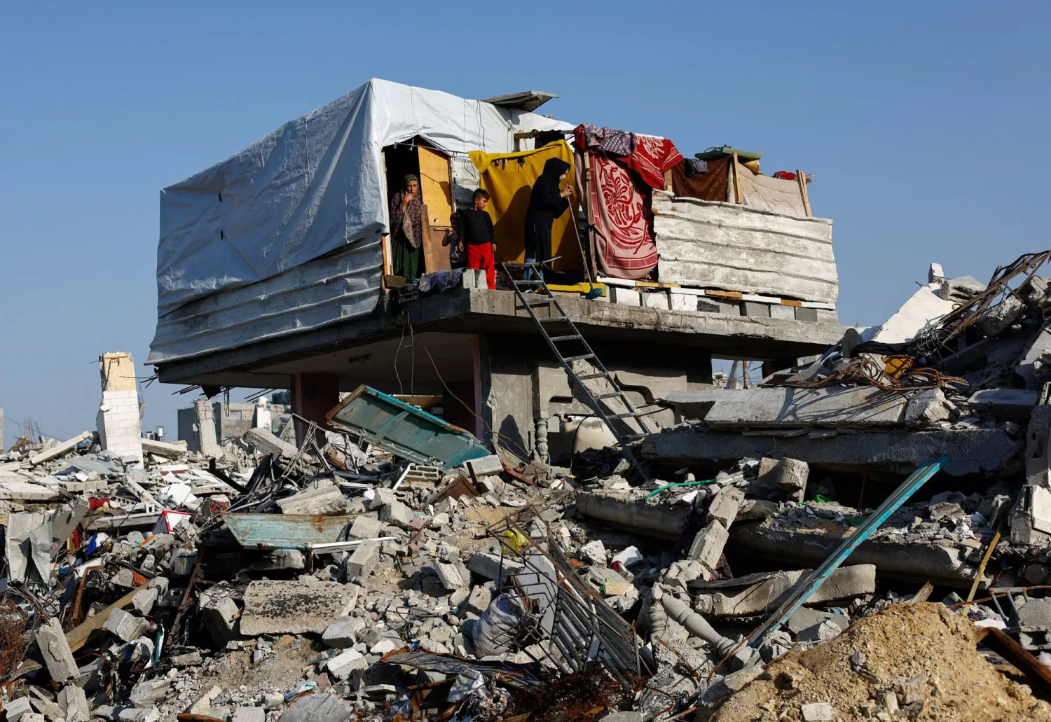 Palestinians stand on the remains of a building among ruins, amid a ceasefire between Israel and Hamas, in the northern Gaza Strip November 19, 2025. REUTERS/Mahmoud Issa