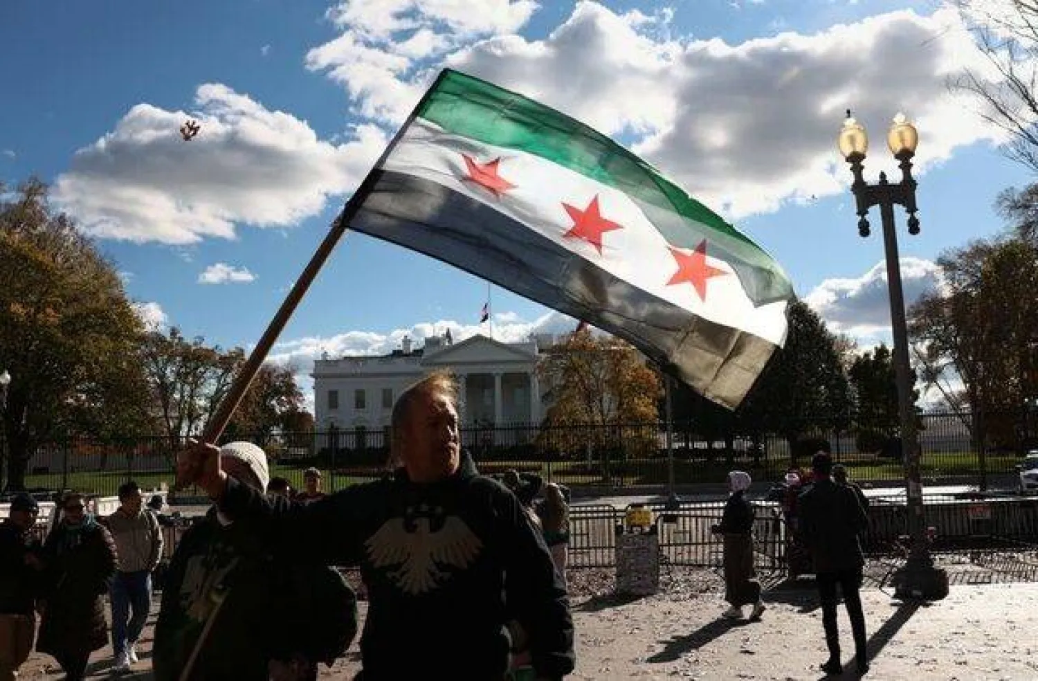 A Syrian flag is held aloft outside the White House following the meeting of US President Donald Trump and Syrian President Ahmed al-Sharaa in the Oval Office of the White House in Washington, D.C., US, November 10, 2025. REUTERS/Kevin Lamarque

