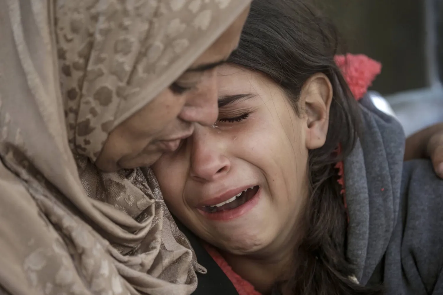 فلسطينية تحتضن ابنة شقيقها الباكية خلال تشييع والدتها التي قُتلت بقصف إسرائيلي في غزة الخميس (إ.ب.أ)
