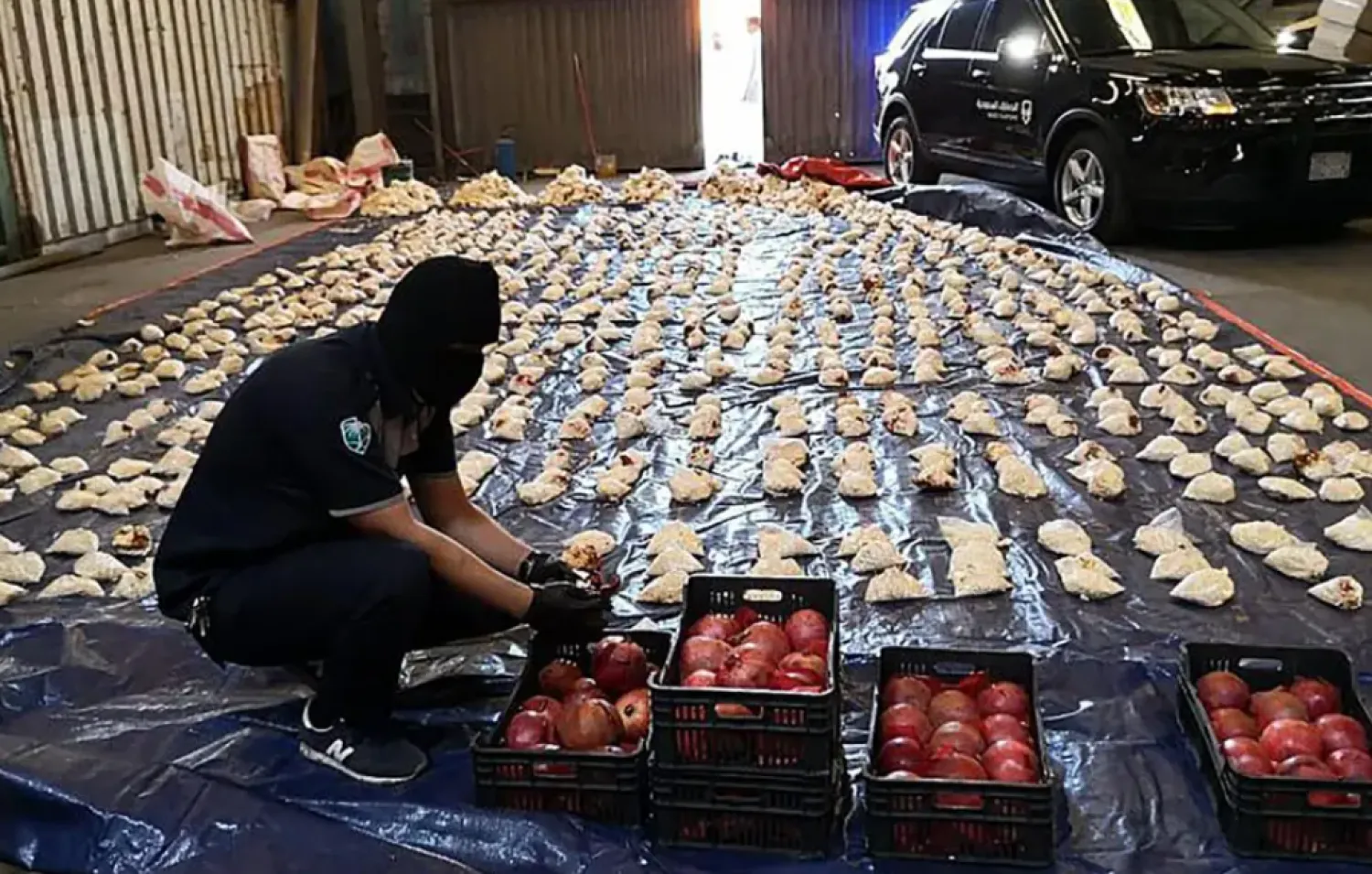 FILE - In this Friday, April 23, 2021 file photo, released by Saudi Press Agency, a Saudi custom officer opens imported pomegranates, as customs foiled an attempt to smuggle over 5 million pills of an amphetamine drug known as Captagon, which they said came from Lebanon, at Jiddah Islamic Port, Saudi Arabia.  (Saudi Press Agency via AP, File)

