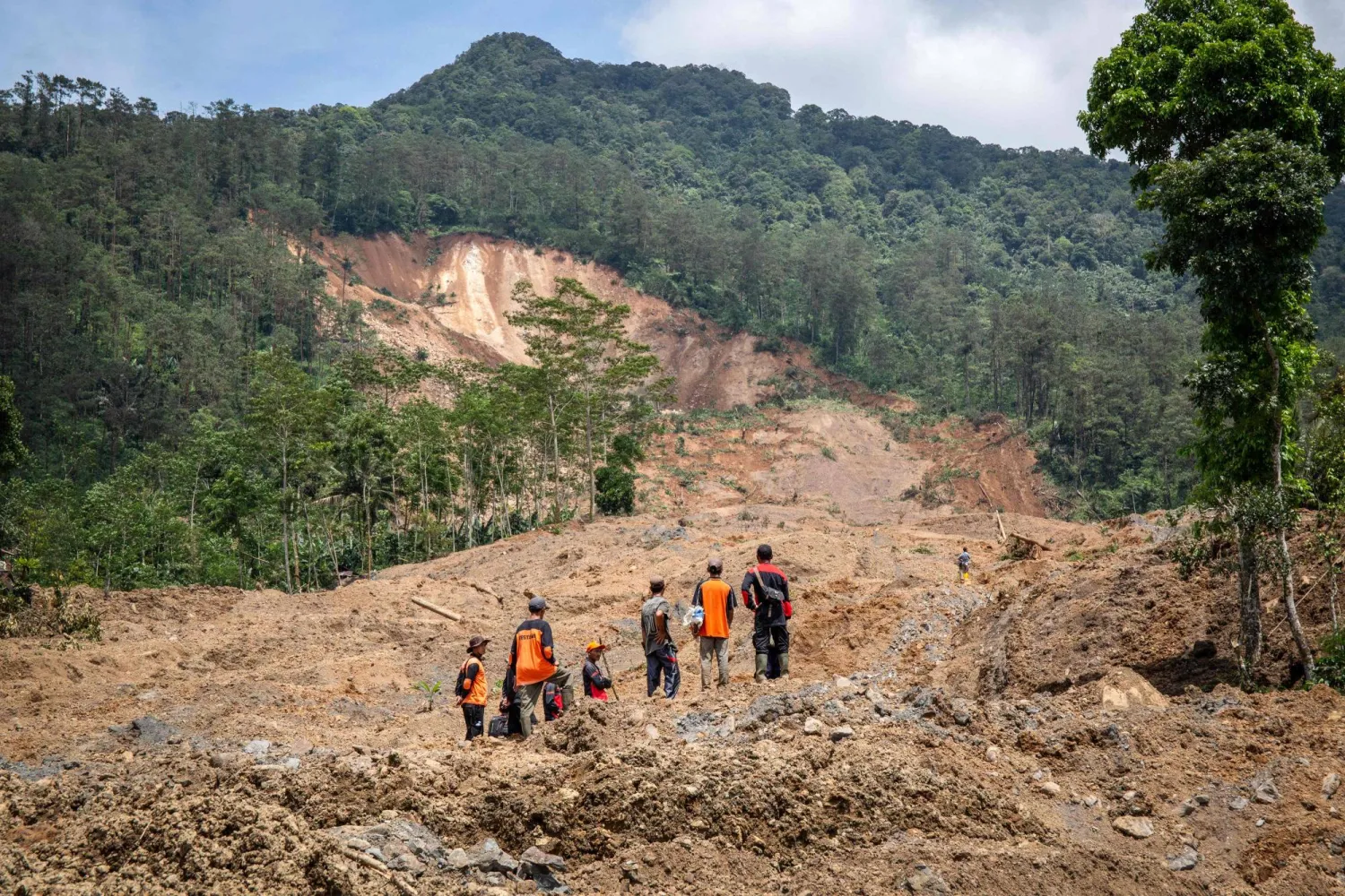Rescue volunteers stand at the site of a landslide in Situkung village, Banjarnegara, Central Java, on November 18, 2025. (Photo by DEVI RAHMAN / AFP)