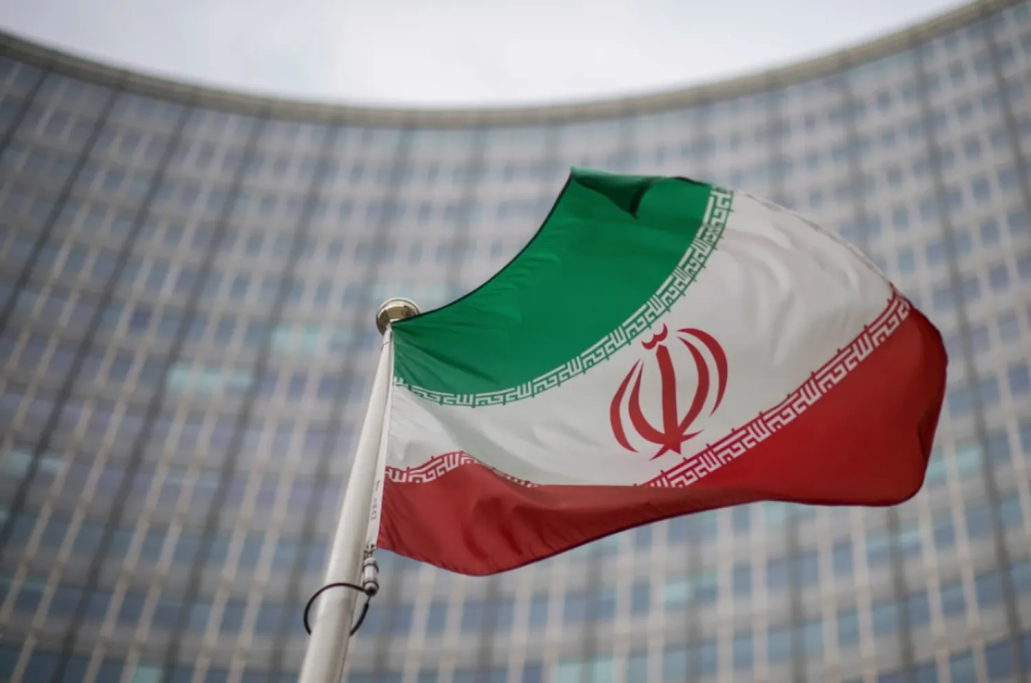 FILE -A national flag of Iran waves in front of the building of the International Atomic Energy Agency, IAEA, in Vienna, Austria, Dec. 17, 2021. (AP Photo/Michael Gruber, File)

