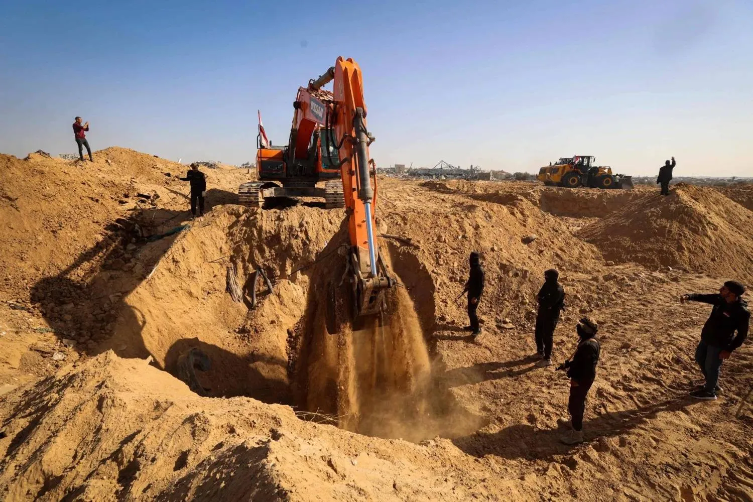 Masked gunmen belonging to the Islamic Jihad movement stand next to an earth mover bearing an Egyptian flag, while searching for the bodies in Nuseirat refugee camp in the central Gaza Strip, on November 21, 2025. (AFP)