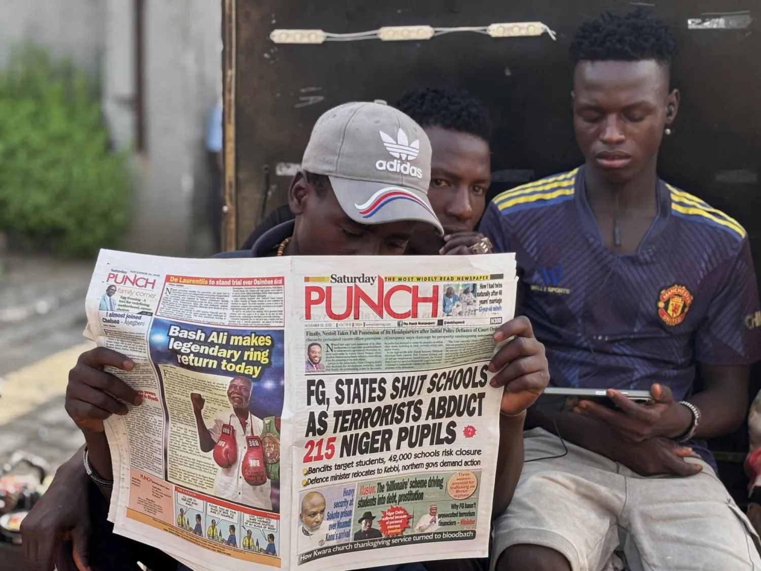 A man in Lagos reads a local newspaper with headlines on gunmen abducting schoolchildren and staff of the St. Mary's Catholic Primary and Secondary School in Papiri community in Nigeria, Saturday, Nov. 22, 2025. (AP Photo/Sunday Alamba )