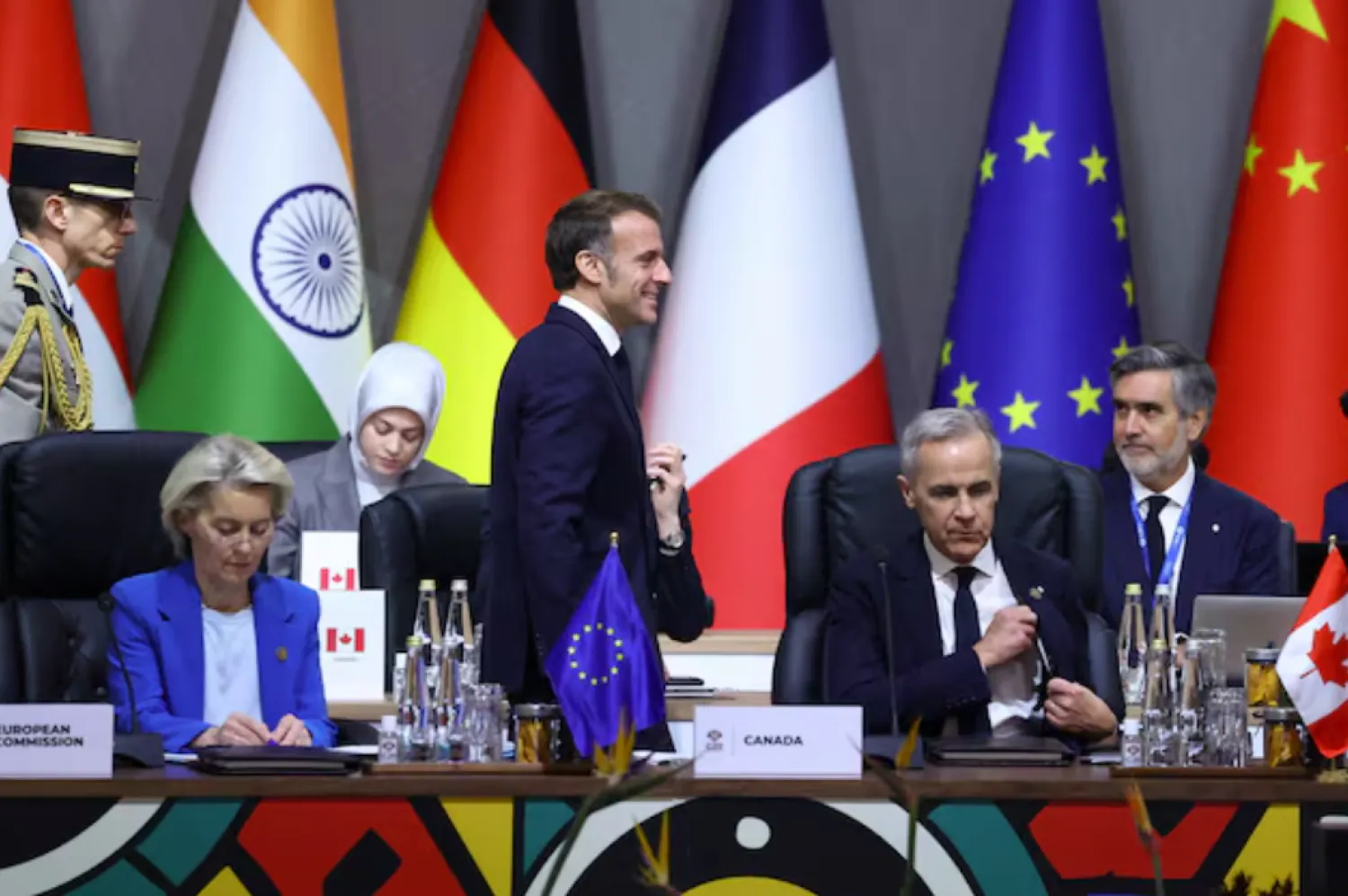 France's President Emmanuel Macron walks past European Commission President Ursula von der Leyen and Canada's Prime Minister Mark Carney during a plenary session on the first day of the G20 Leaders' Summit at the Nasrec Expo Centre in Johannesburg, South Africa, November 22, 2025. REUTERS/Yves Herman P