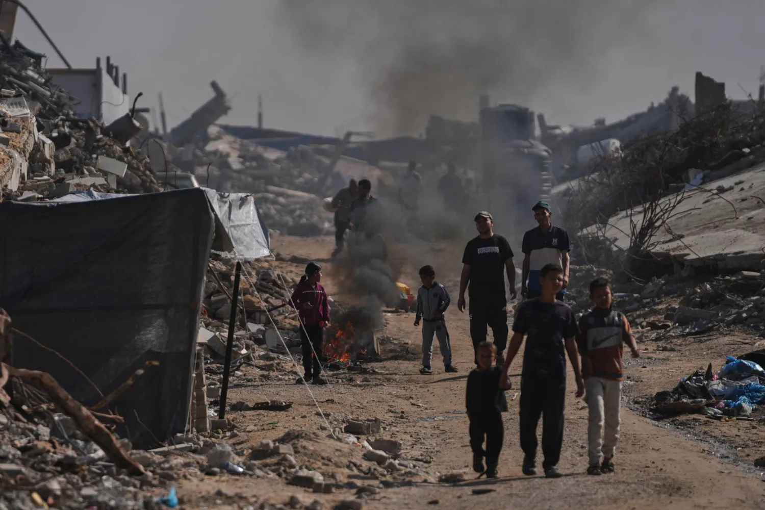 نازحون فلسطينيون يشعلون ناراً لإبعاد البعوض وسط الدمار الذي خلفه القصف الجوي والمدفعي الإسرائيلي في جباليا (أ.ب)