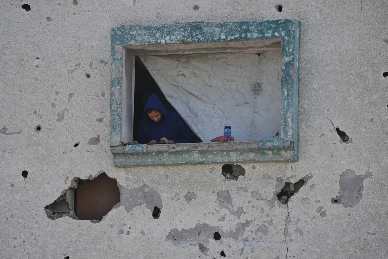 Gazze Şeridi'nin kuzeyindeki Cibaliye bölgesinde, hasar görmüş evinin penceresinden dışarı bakan Filistinli bir kadın, 21 Kasım 2025 (AP)