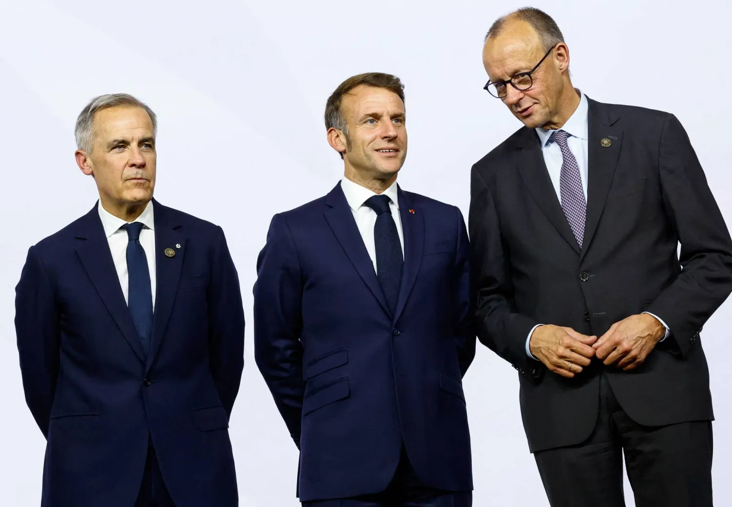Canada's Prime Minister Mark Carney, France’s President Emmanuel Macron and Germany's Chancellor Friedrich Merz stand together, as they attend a family photo event, on the opening day of the G20 Leader's Summit at the Nasrec Expo Centre in Johannesburg, South Africa, November 22, 2025. REUTERS/Thomas Mukoya/Pool