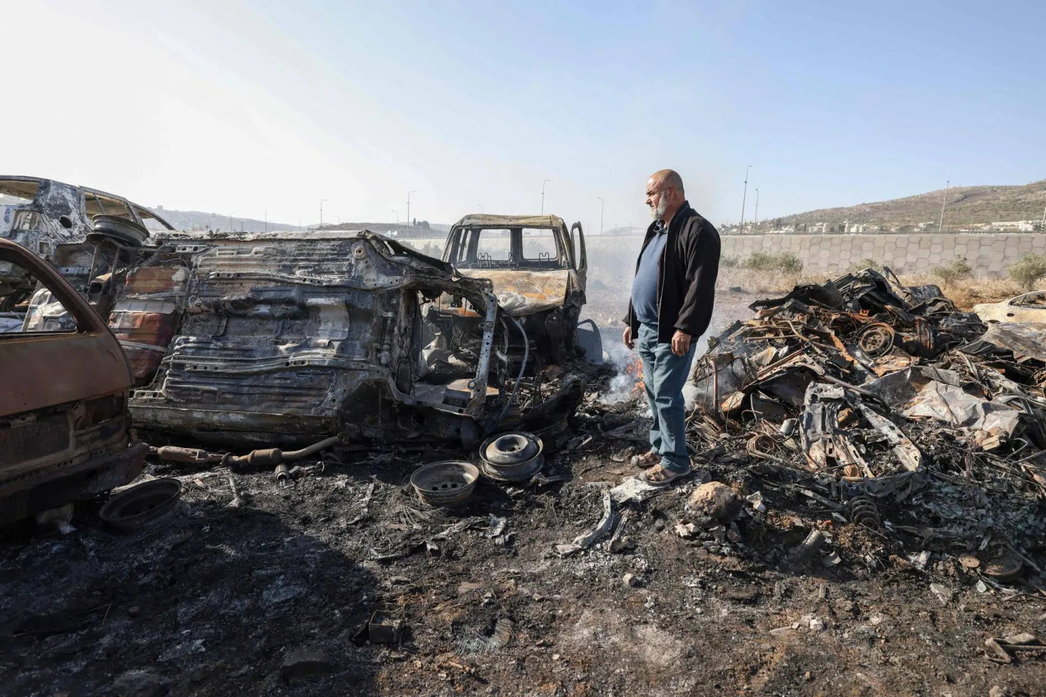 A Palestinian man Ahmad Dalal, 57, inspects scrap cars burnt in an attack by Israeli settlers, in Huwara in the Israeli-occupied West Bank, November 21, 2025.  (Photo by JAAFAR ASHTIYEH / AFP)