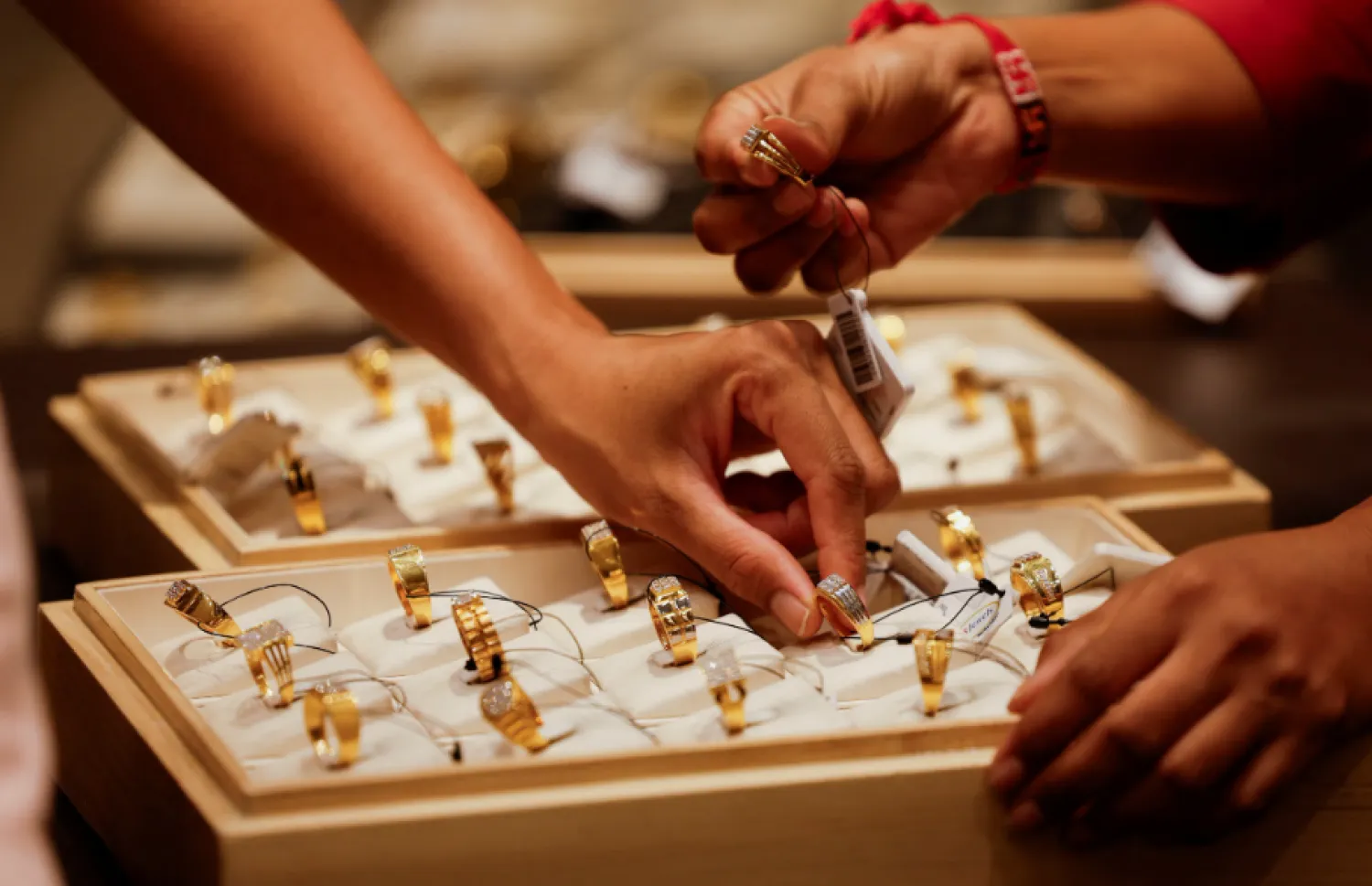 A salesperson shows a gold ring to customers at a jewellery showroom in Ahmedabad, India, October 8, 2025. REUTERS/Amit Dave
