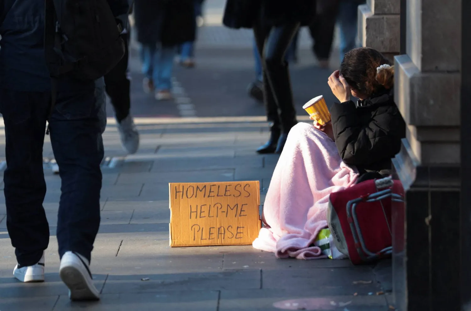 شخص من دون مأوى يتوسل بينما تواجه وزيرة الخزانة البريطانية راشيل ريفز قرارات مالية صعبة (رويترز)