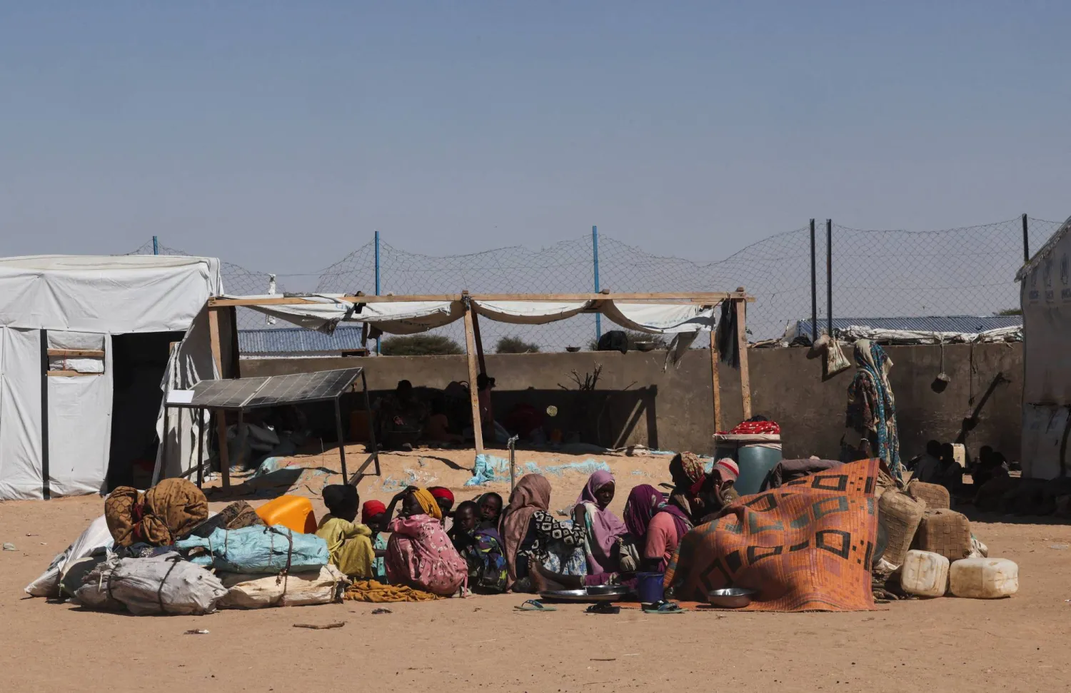 لاجئون سودانيون وصلوا حديثاً من الفاشر هرباً من الاشتباكات المستمرة بين «قوات الدعم السريع» والجيش السوداني يجلسون على الأرض داخل مخيم في شرق دولة تشاد... 23 نوفمبر 2025 (رويترز)