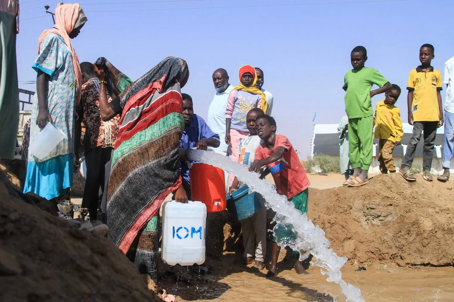 Sudanese who fled El-Fasher in Darfur fill jerrycans with water at the Al-Afad camp for displaced people in the town of Al-Dabbah, northern Sudan, on November 21, 2025. (Photo by Ebrahim Hamid / AFP)