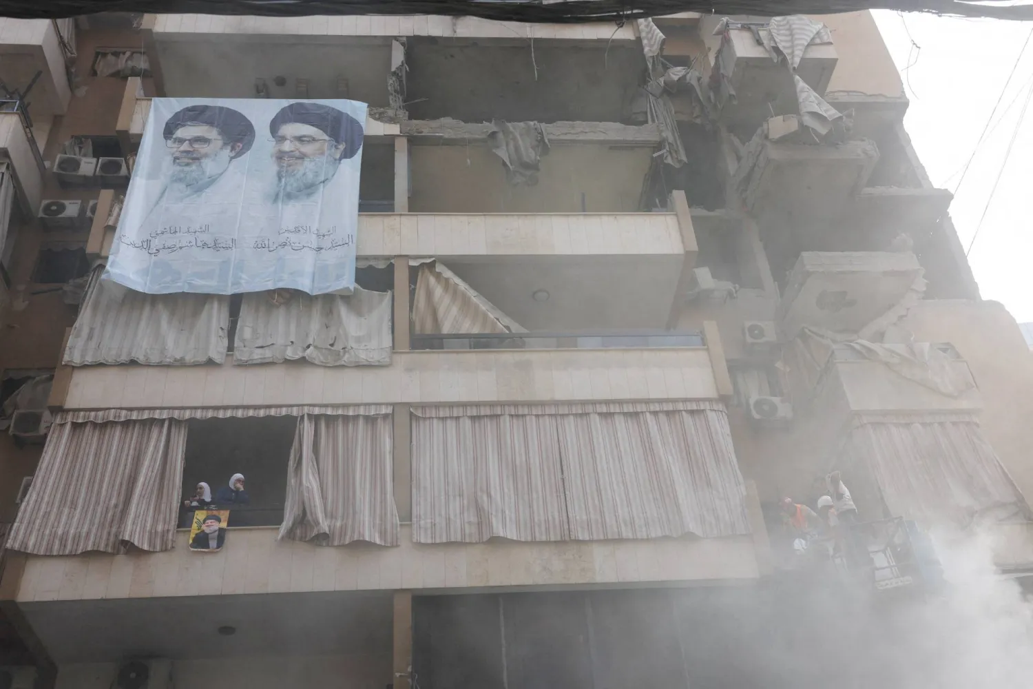 لافتة تُظهر زعيمَي «حزب الله» الراحلين الأسبق حسن نصر الله والسابق هاشم صفي الدين موضوعة بموقع غارة إسرائيلية على مبنى استُهدف فيه الطبطبائي (رويترز)