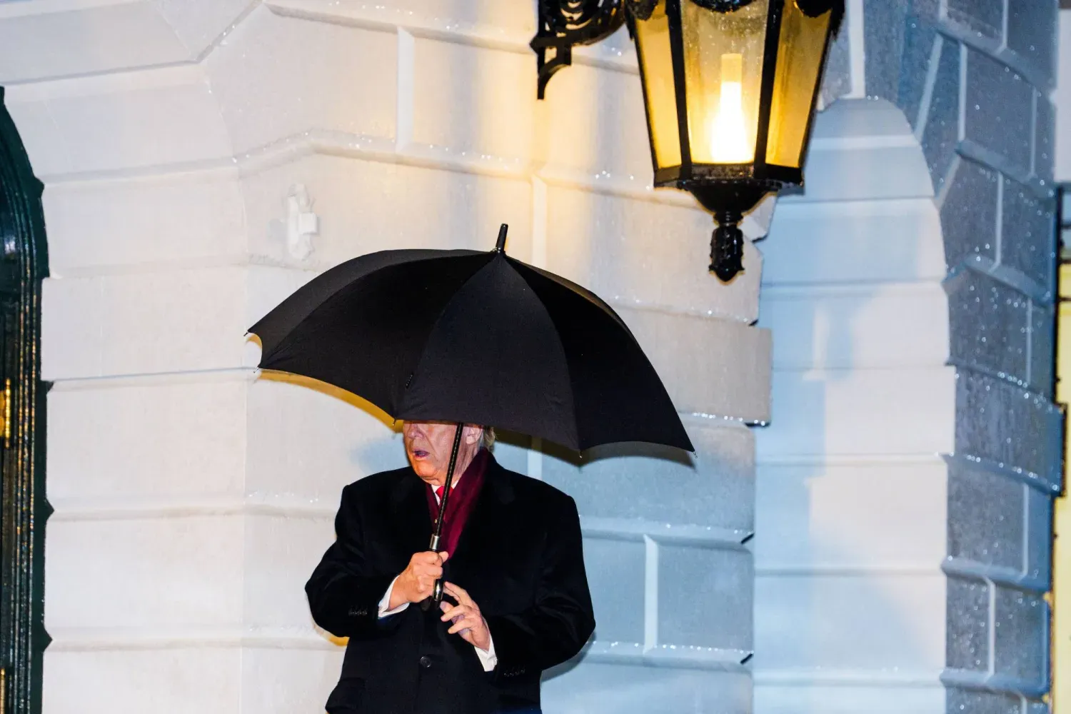 ABD Başkanı Donald Trump, Beyaz Saray'ın girişinde yağmurdan korunmak için şemsiyesiyle (EPA)