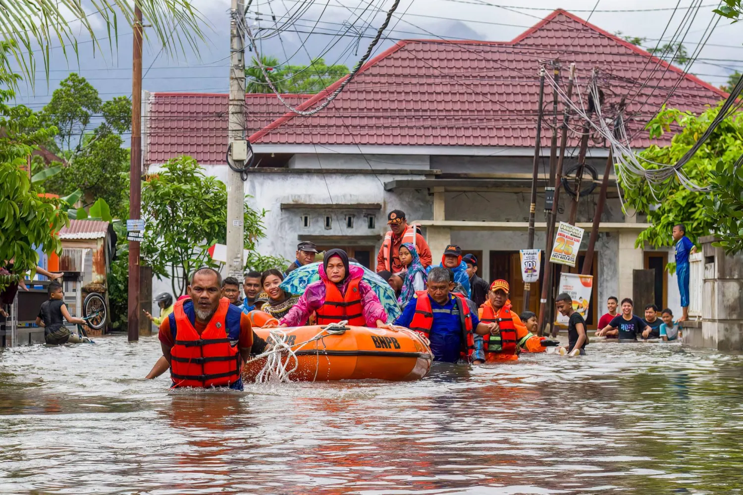 A rescue team evacuates women and children in a rubber boat as floodwaters hit a residential area in Padang, West Sumatra on November 25, 2025. (AFP)