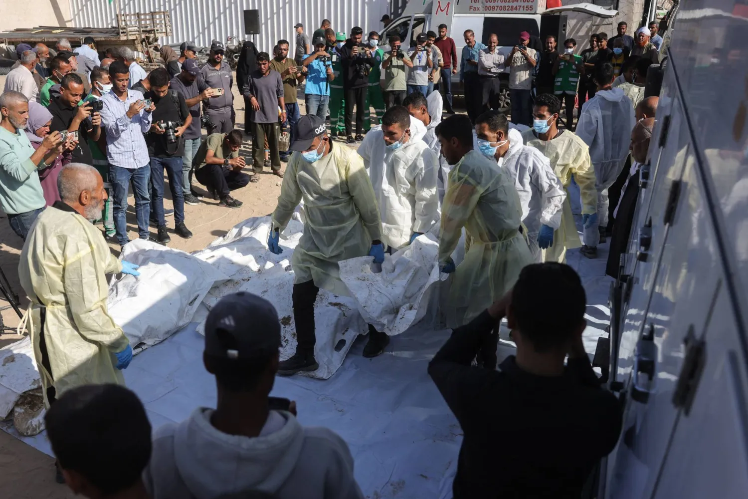 موظفو مستشفى ناصر يستخرجون رفات فلسطينيين مجهولين من شاحنة مبردة في خان يونس بعد أن أعادتهم إسرائيل بموجب اتفاق وقف إطلاق النار (أ.ف.ب)