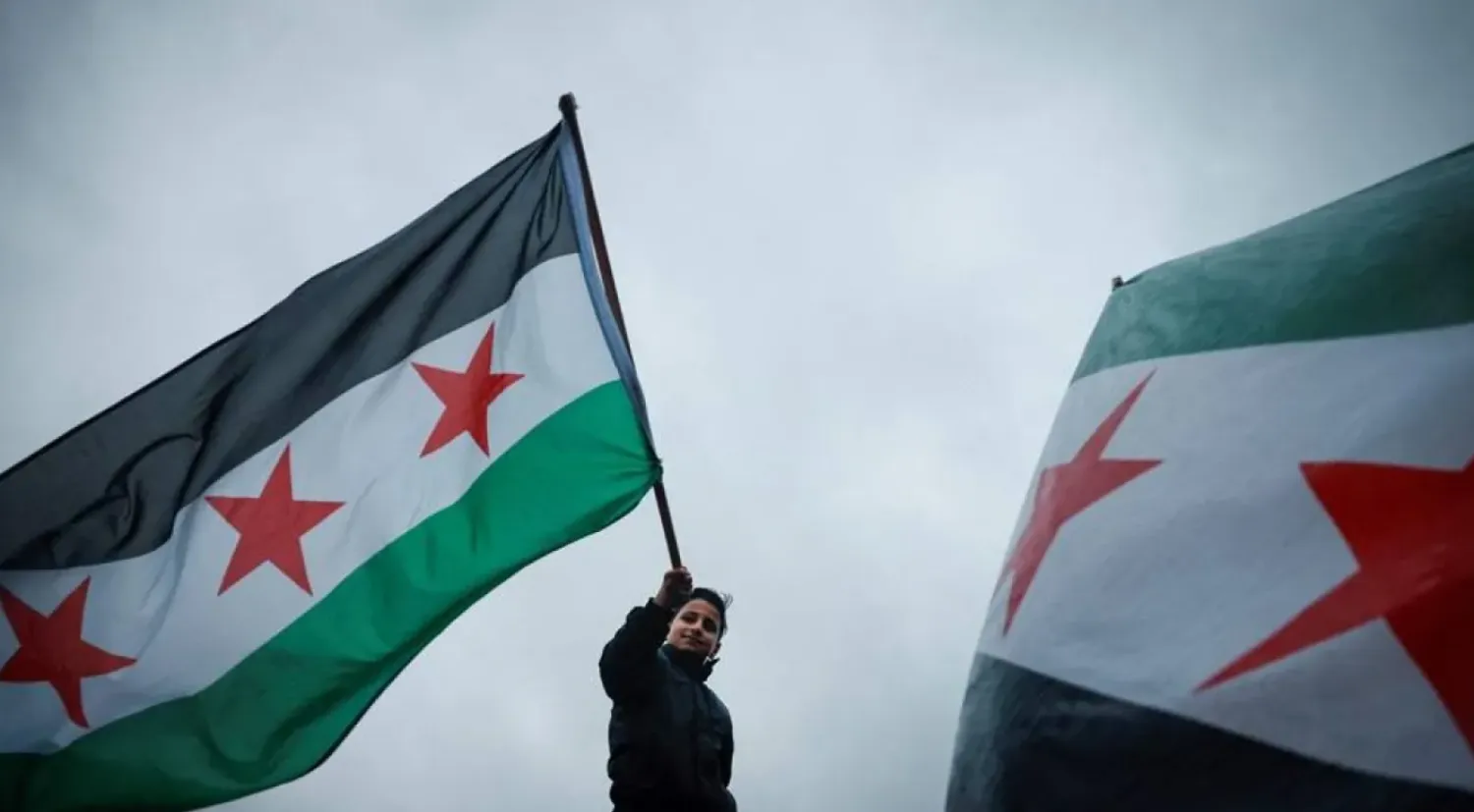 A demonstrator waves the Syrian opposition flag, also known as the revolution flag, during a gathering with other supporters and members of the Syrian community called by the Syria Solidarity Campaign group in Trafalgar Square, central London, on December 8, 2024, to celebrate the fall of the Assad regime. (AFP)
