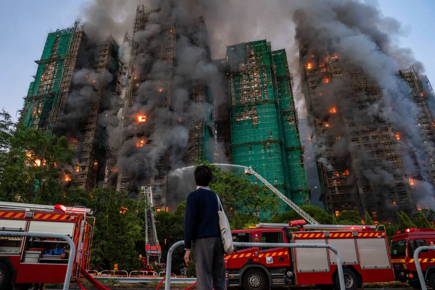 26 November 2025, China, Hong Kong: A student watches Smoke and flames rising as a major fire engulfs several residential buildings at Wang Fuk Court in Hong Kong. Photo: Vernon Yuen/Nexpher via ZUMA Press Wire/dpa
