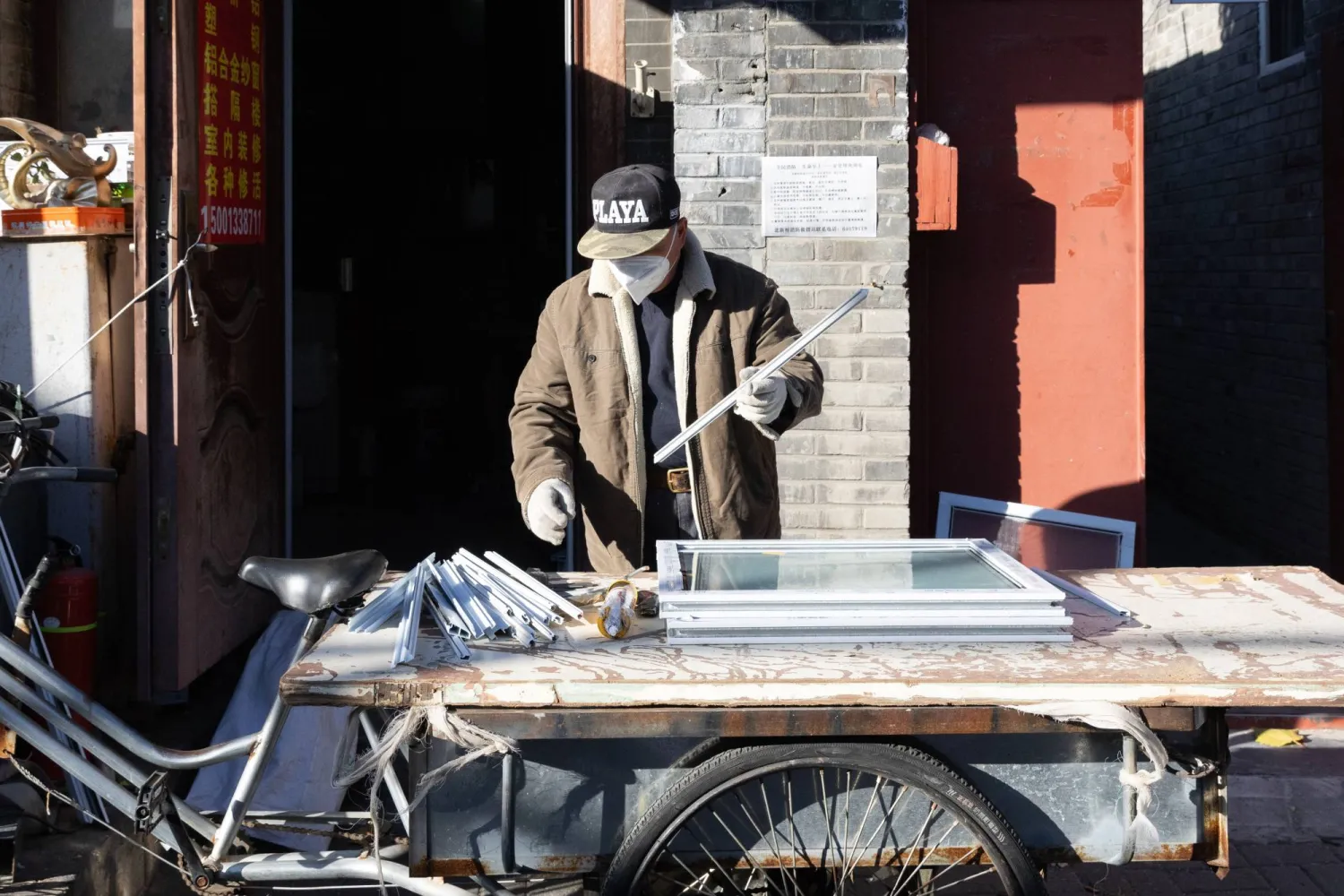 عامل يقوم بفرز بعض المعادن أمام مصنع صغير في العاصمة الصينية بكين (إ.ب.أ)