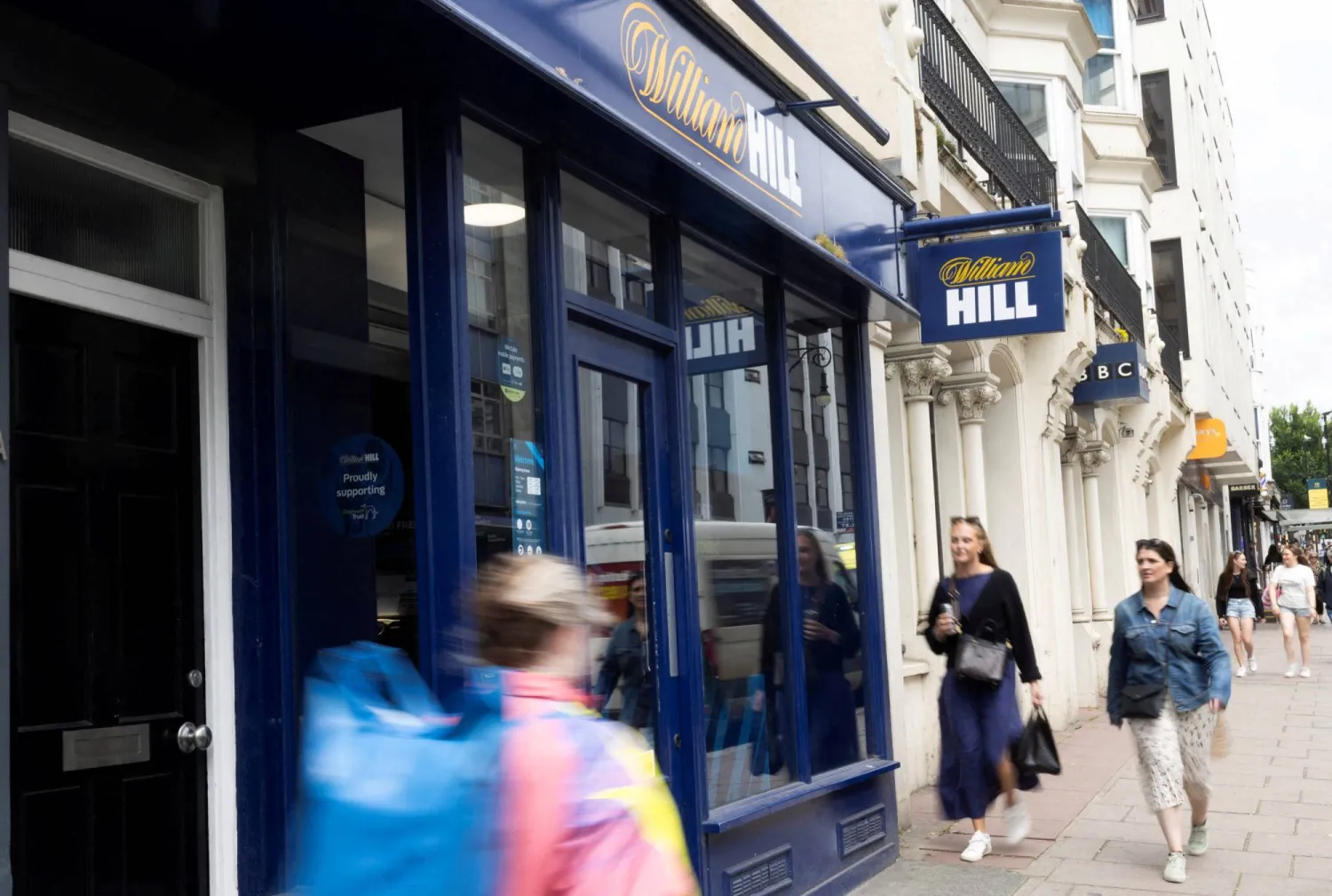 أشخاص يمرون أمام متجر مراهنات في برايتون بريطانيا (رويترز)