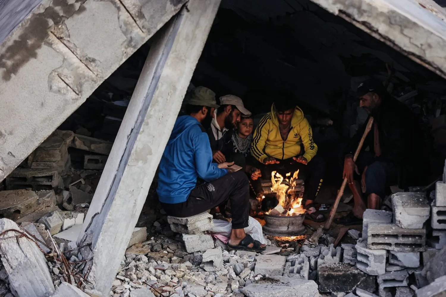 نازحون فلسطينيون يستدفئون بالنار بعد تدمير منازلهم إثر هطول أمطار غزيرة في مدينة غزة أخيراً (أ.ف.ب)