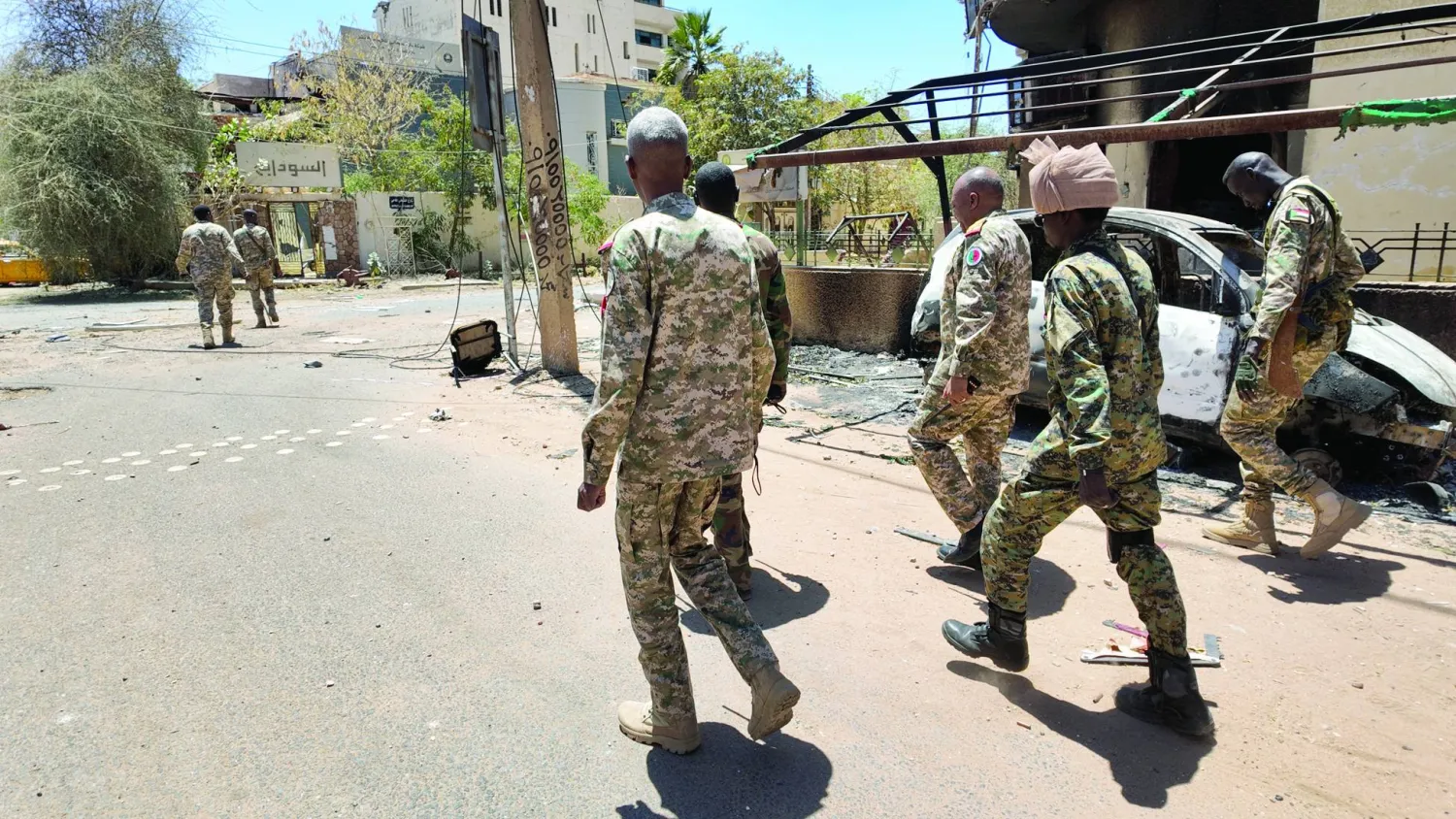 أفراد من الجيش السوداني يسيرون بجوار مركبات عسكرية مدمرة في الخرطوم (رويترز)