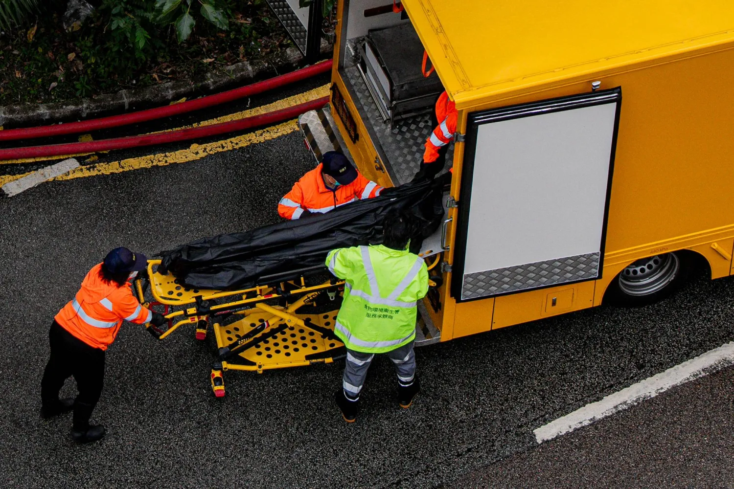 مسعفون ينقلون جثمان إحدى ضحايا الحريق بمنطقة تاي بو في هونغ كونغ (إ.ب.أ)