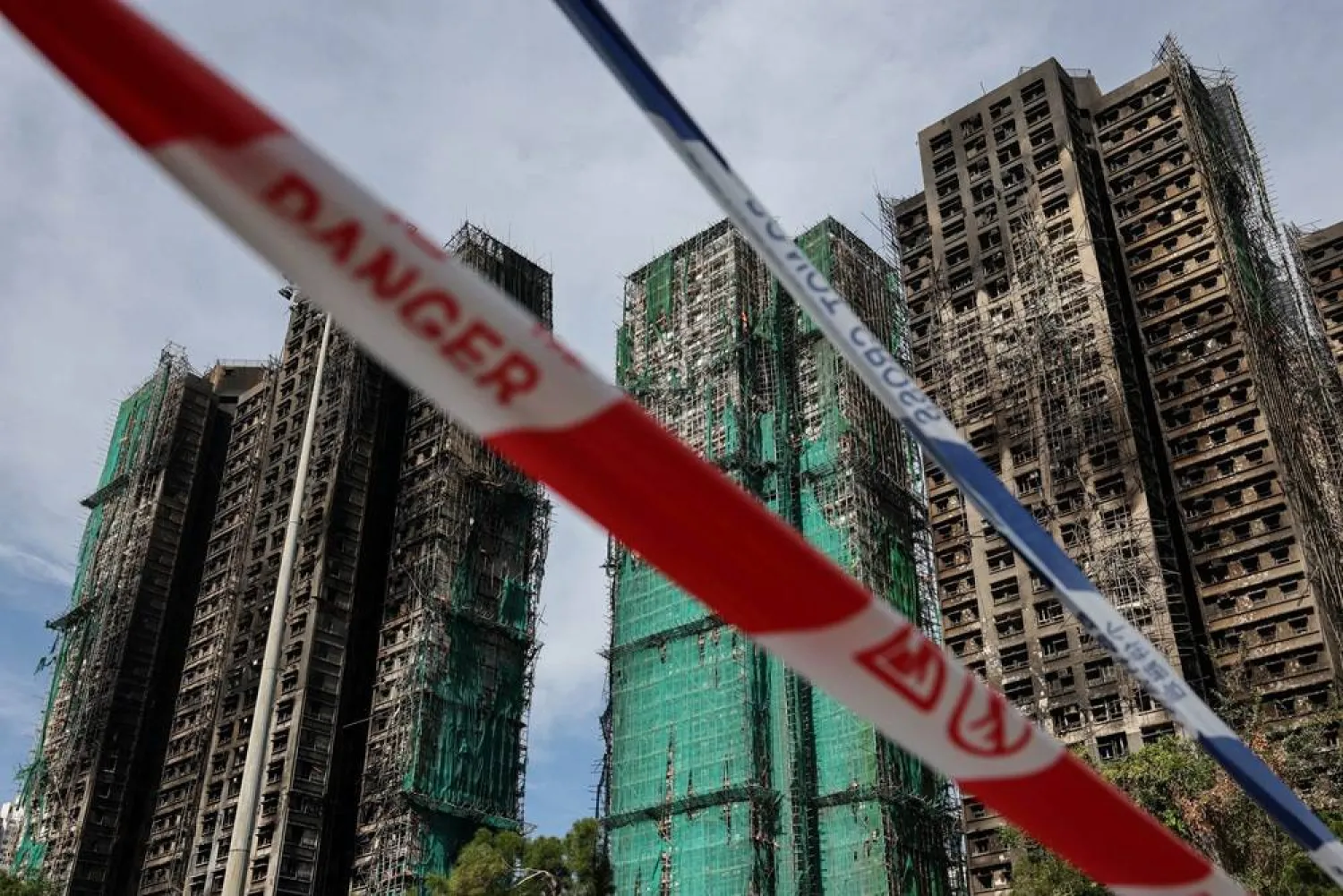  Police cordons are placed at the scene of the Wang Fuk Court housing estate fire as mourners pay tribute to the victims, in Tai Po, Hong Kong, China, November 28, 2025. (Reuters)