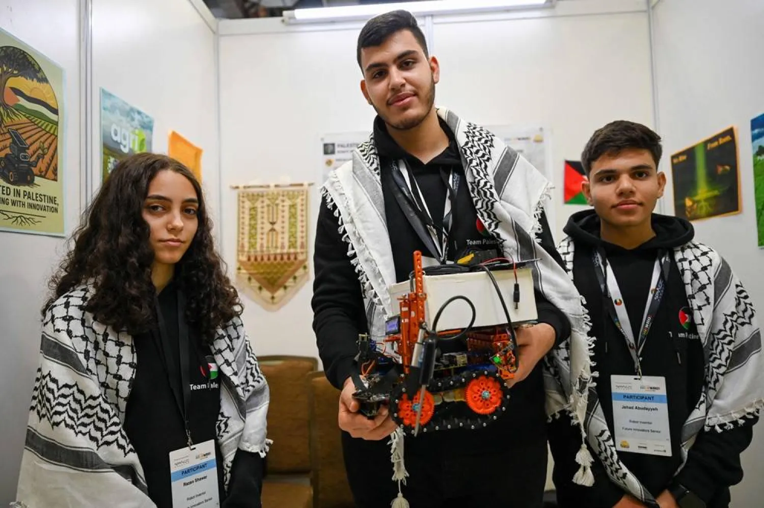 Palestinian participants Razan Shawar (L), Jehad Abudayyah (R), and Mustafa Assi (C) pose with their robot design for the Future Innovators category at the World Robot Olympiad in Singapore on November 28, 2025. (AFP) 