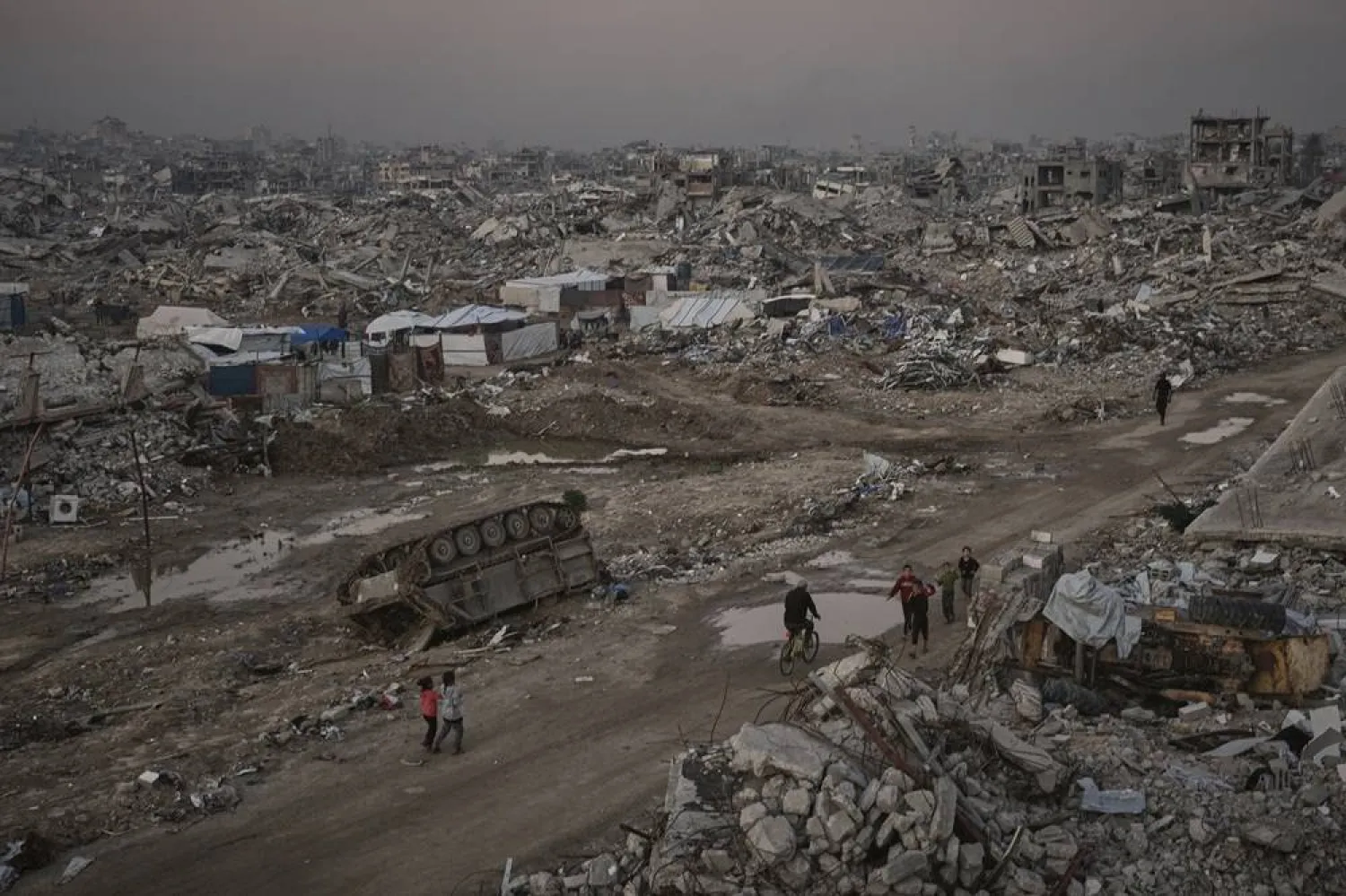  Palestinians walk past a destroyed Israeli armored vehicle amid widespread devastation in Gaza City Thursday, Nov. 27, 2025. (AP) 