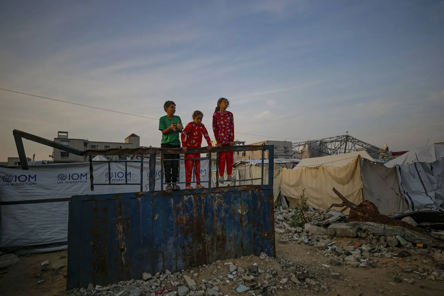 أطفال فلسطينيون نازحون يلعبون بالقرب من ملاجئ عائلاتهم وسط أنقاض المباني المُدمَّرة في مدينة غزة (إ.ب.أ)