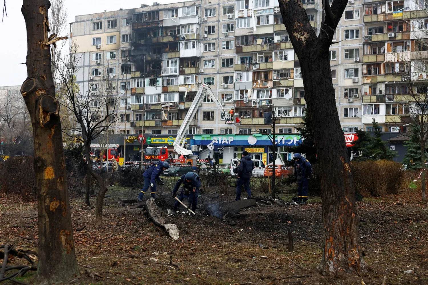 أفراد من خدمات الطوارئ يتفقدون حفرة بالقرب من مبنى سكني في أعقاب هجوم صاروخي روسي على كييف (رويترز)