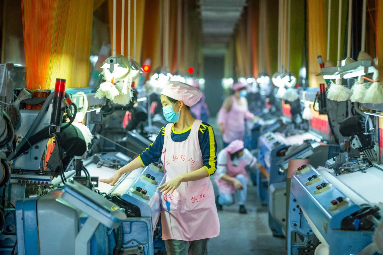 عمال ينتجون أقمشة الجاكار لطلبيات التصدير لمصنع في نانتونغ بمقاطعة جيانغسو شرق الصين (أ.ف.ب)