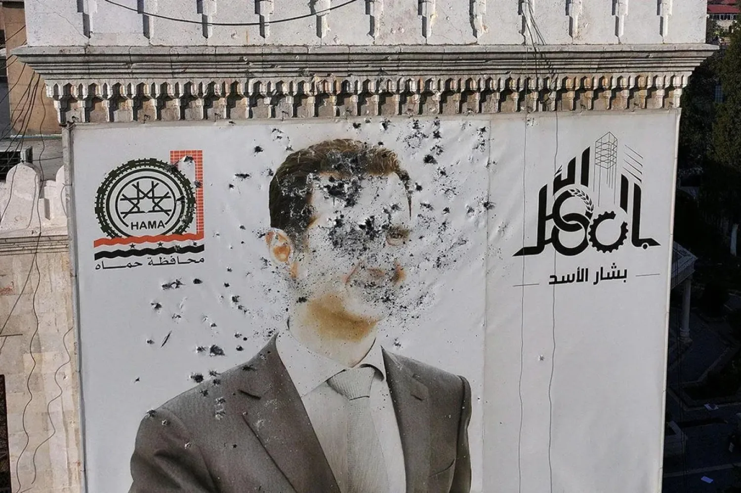 HTŞ öncülüğündeki isyancılar, Suriye'yi ele geçirirken Esad'ın posterlerini parçalamıştı (AFP)