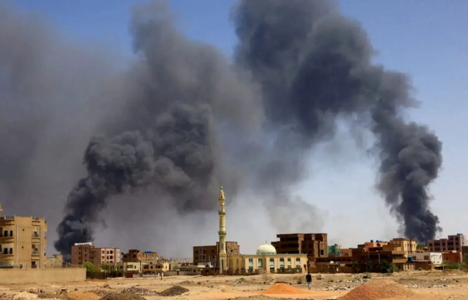 A man walks while smoke rises above buildings after aerial bombardment, during clashes between the Rapid Support Forces and the army in Khartoum North, Sudan, May 1, 2023. REUTERS/Mohamed Nureldin Abdallah/File Photo