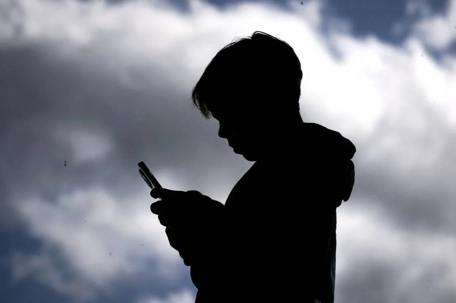 This photo taken on October 24, 2025 shows a 14-year-old boy posing at his home near Gosford as he looks at social media on his mobile phone. (AFP)