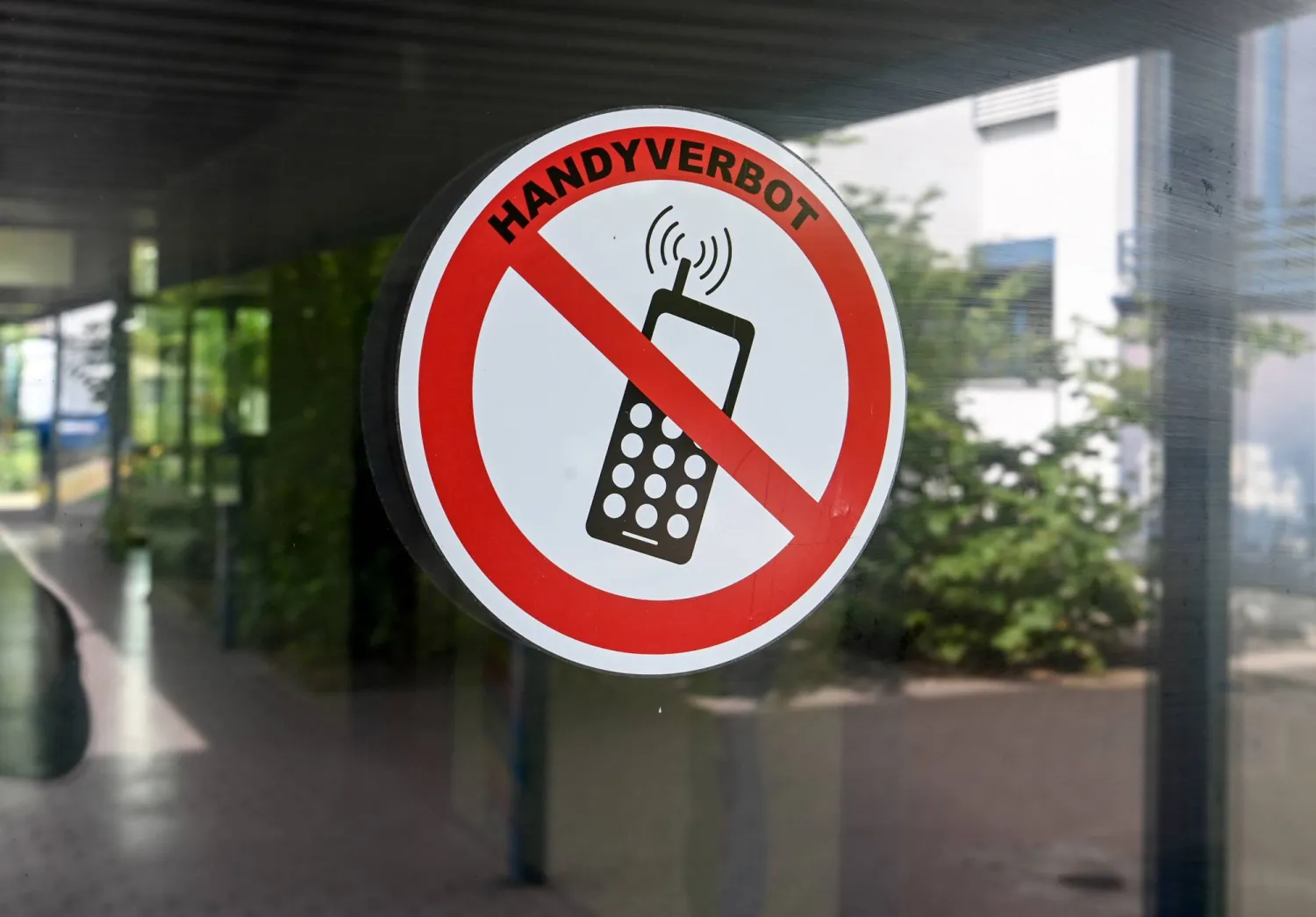 FILED - 22 August 2022, Berlin: A "no cell phones" sign is posted at the entrance to a school in Neukoelln, Germany. Photo: Jens Kalaene/dpa