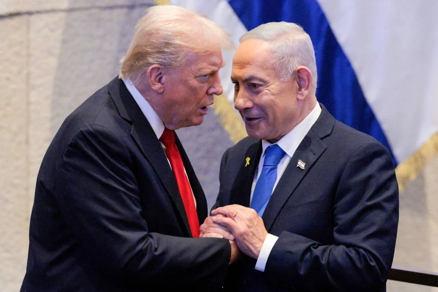 (FILES) US President Donald Trump (L) holds hands and speaks with Israeli Prime Minister Benjamin Netanyahu at the Israeli parliament, the Knesset, in Jerusalem on October 13, 2025. (Photo by Chip Somodevilla / POOL / AFP)