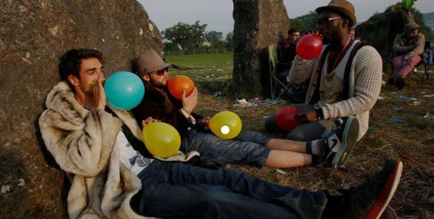 أشخاص يستنشقون غاز الضحك باستخدام البالونات (رويترز)