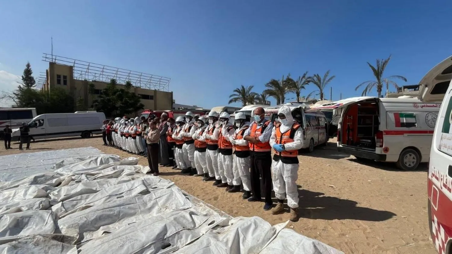 عناصر من الدفاع المدني الفلسطيني يؤدون صلاة الجنازة على عدد من الجثامين قبل دفنهم (الدفاع المدني الفلسطيني عبر «تلغرام»)