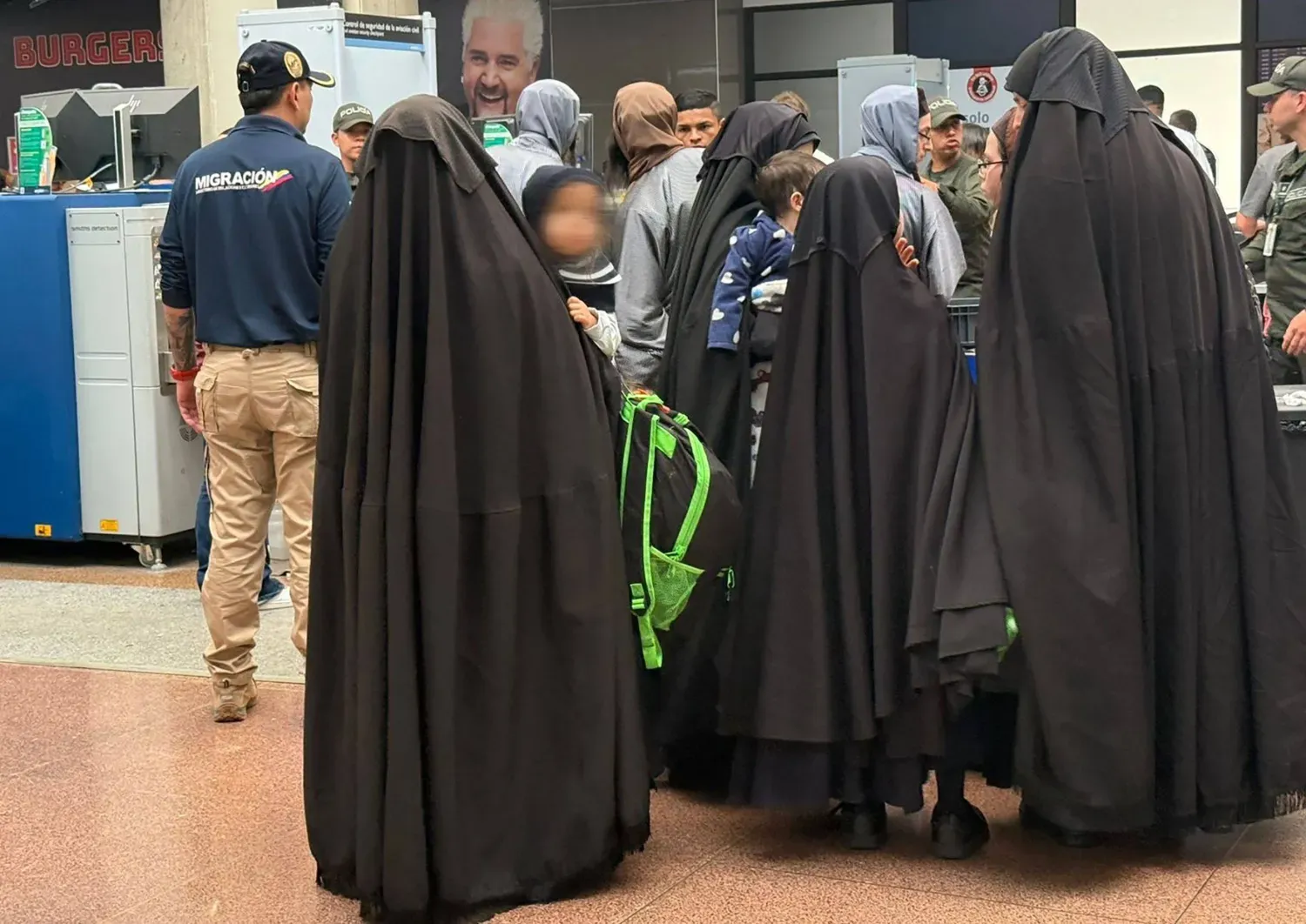 Yetkililer tarafından yayımlanan fotoğraflarda, Lev Tahor tarikatına mensup kişilerin havaalanı güvenlik noktalarından geçerken uzun siyah ceketler giydiği görülüyor (AFP)