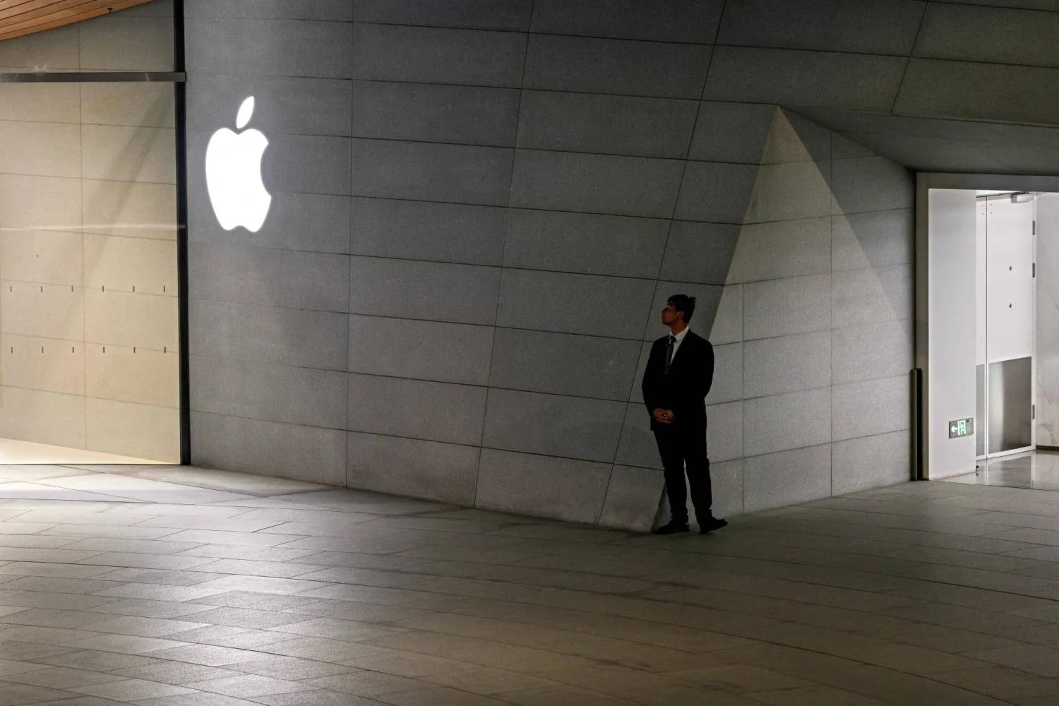 A guard stands next to a store of US tech giant Apple Inc. in the Jing'an district in Shanghai on November 4, 2025. (Photo by Hector RETAMAL / AFP)