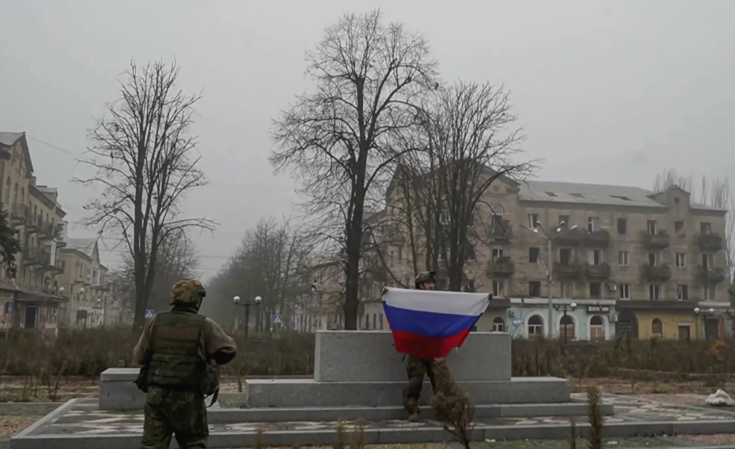 جندي روسي يرفع علم بلاده في إحدى البلدات بإقليم دونيستك الأوكراني الثلاثاء (إ.ب.أ)