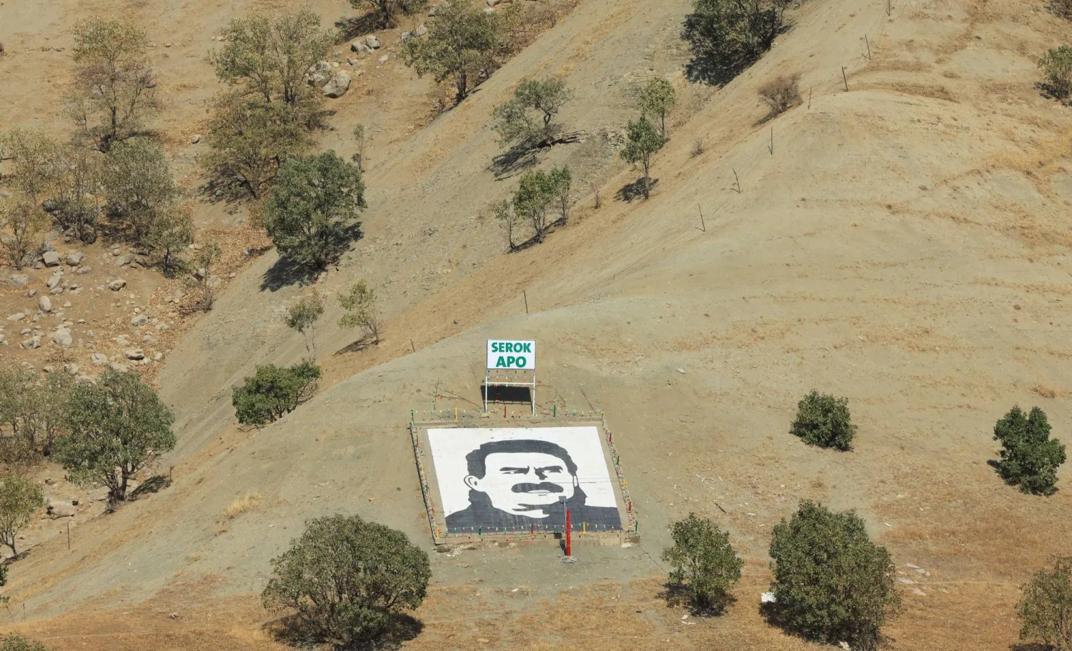صورة لزعيم حزب العمال الكردستاني السجين عبد الله أوجلان ثبتها مسلحون من الحزب عند سفح جبل قنديل شمال العراق عند إعلان انسحابهم من تركيا في 26 أكتوبر الماضي (رويترز)